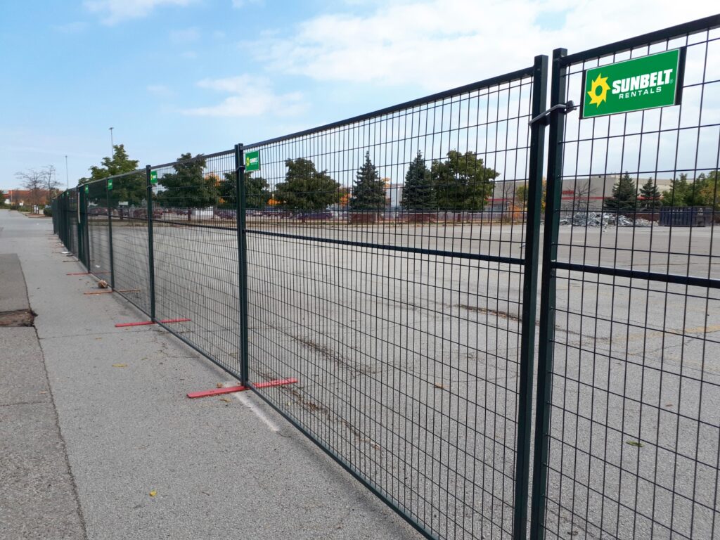 Une clôture temporaire en acier vert foncé de 6 pieds de haut devant un parc.