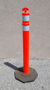 A high-visibility orange plastic delineator with reflective tape and a black rubber base.