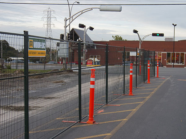 Temporary metal fencing with high-visibility delineators surrounds a construction site.