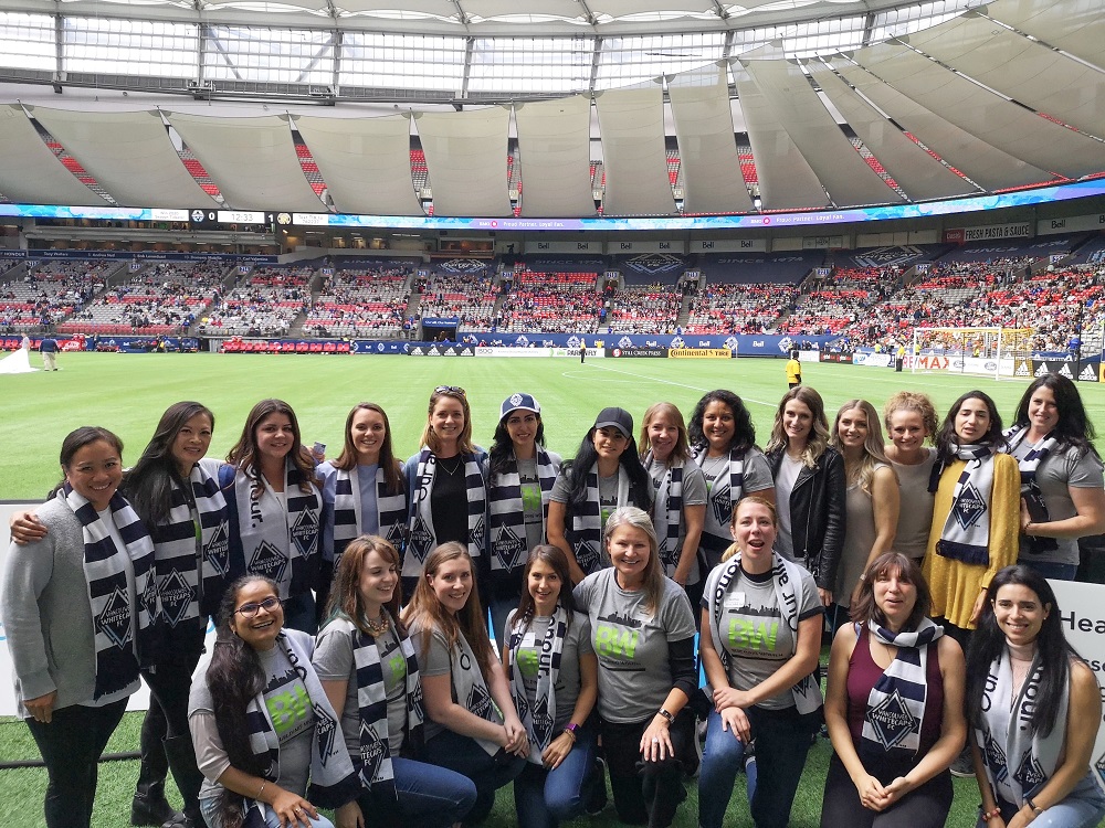 A photo of a large group of female construction employees, taken in front of the pitch at BC Place