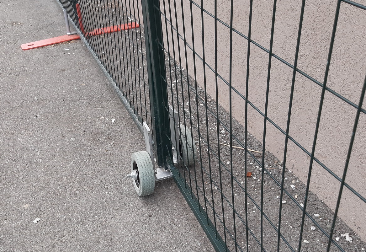 A close-up of two overlapping fence panels with gate wheels, forming a double sliding gate