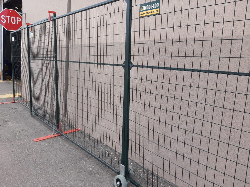 A photo of a double sliding gate constructed from 6' tall dark green steel temporary fence panels